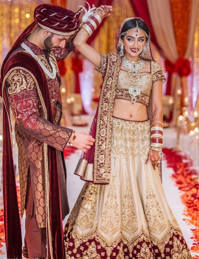 Maroon and cream colored Punjabi bridal lehenga with heavy gota patti, zari and embroidery work