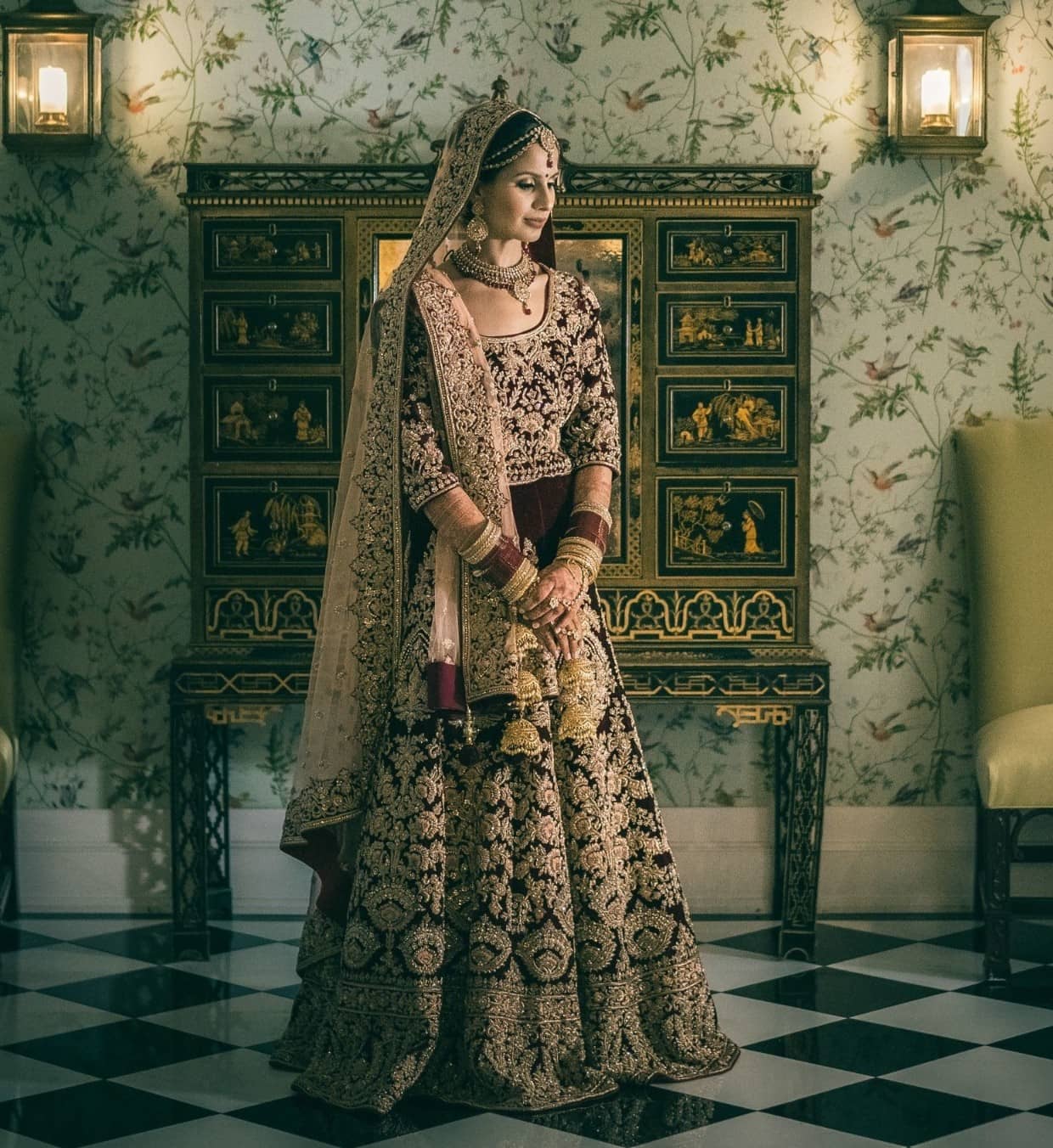 Punjabi bride wearing wine colored bridal lehenga with golden zari and thread work