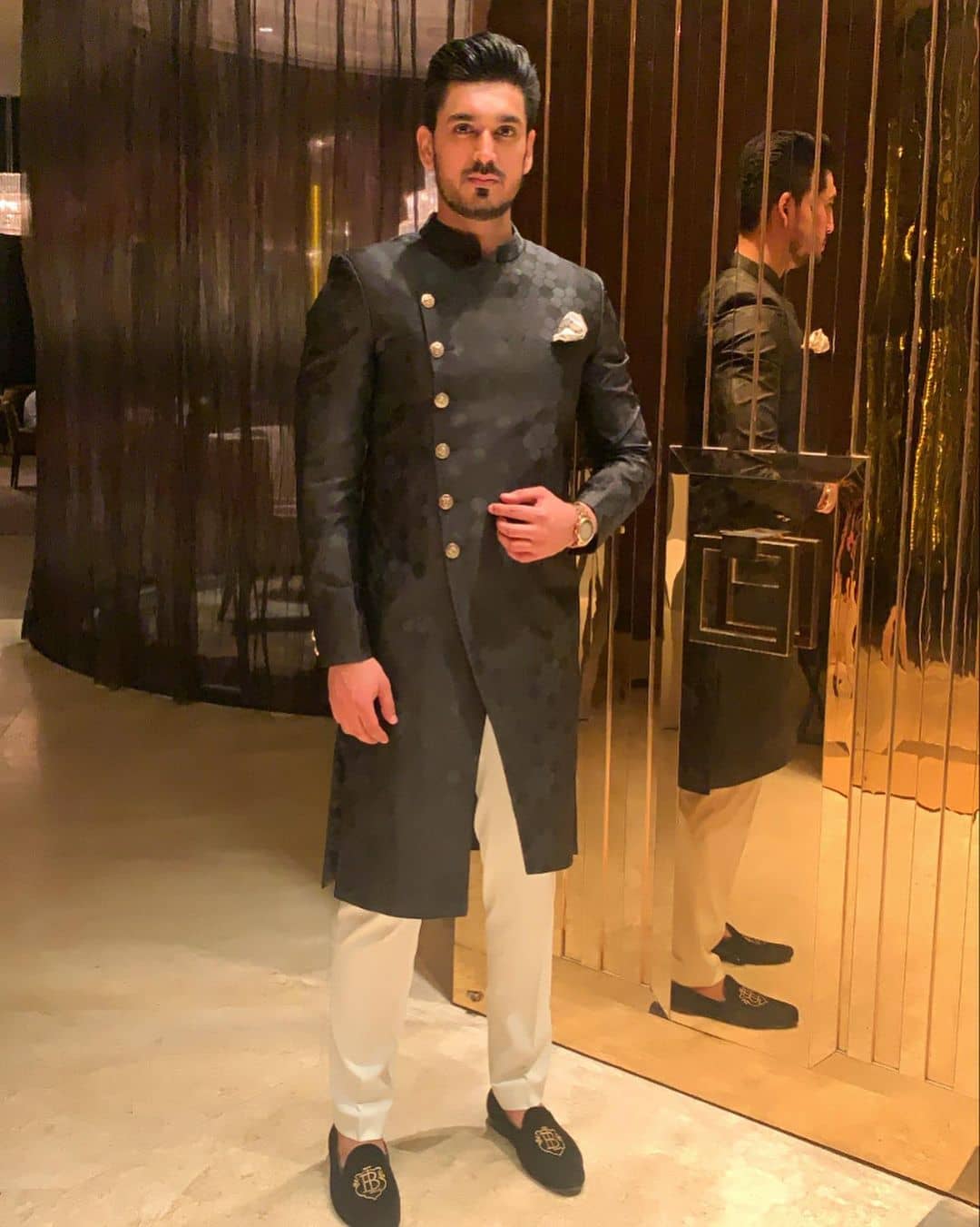 Front slit black sherwani with golden buttons and off-white pants